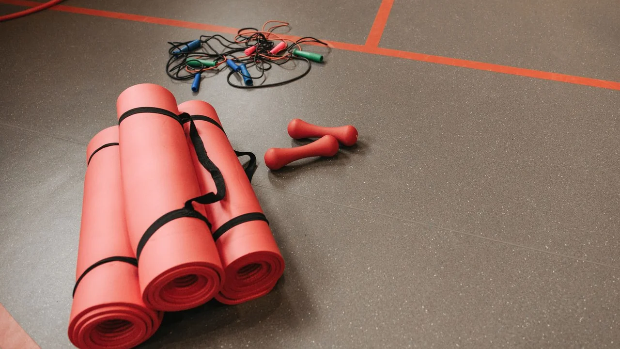 Rolled exercise mats, small dumbbells and skipping ropes on a gym floor