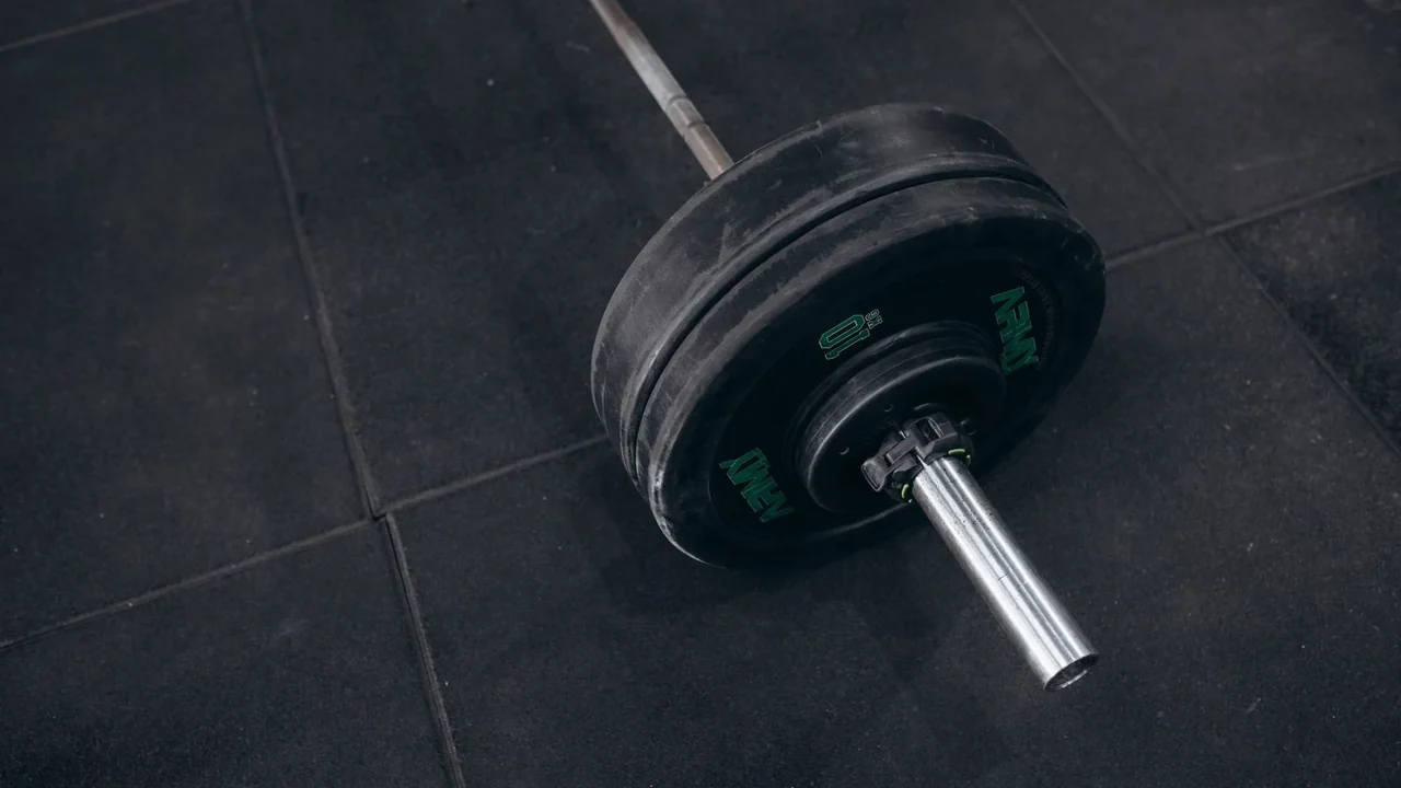 A barbell resting on a tiled gym floor