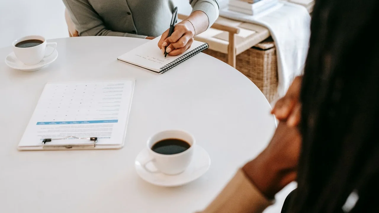 Two people taking notes across a small table