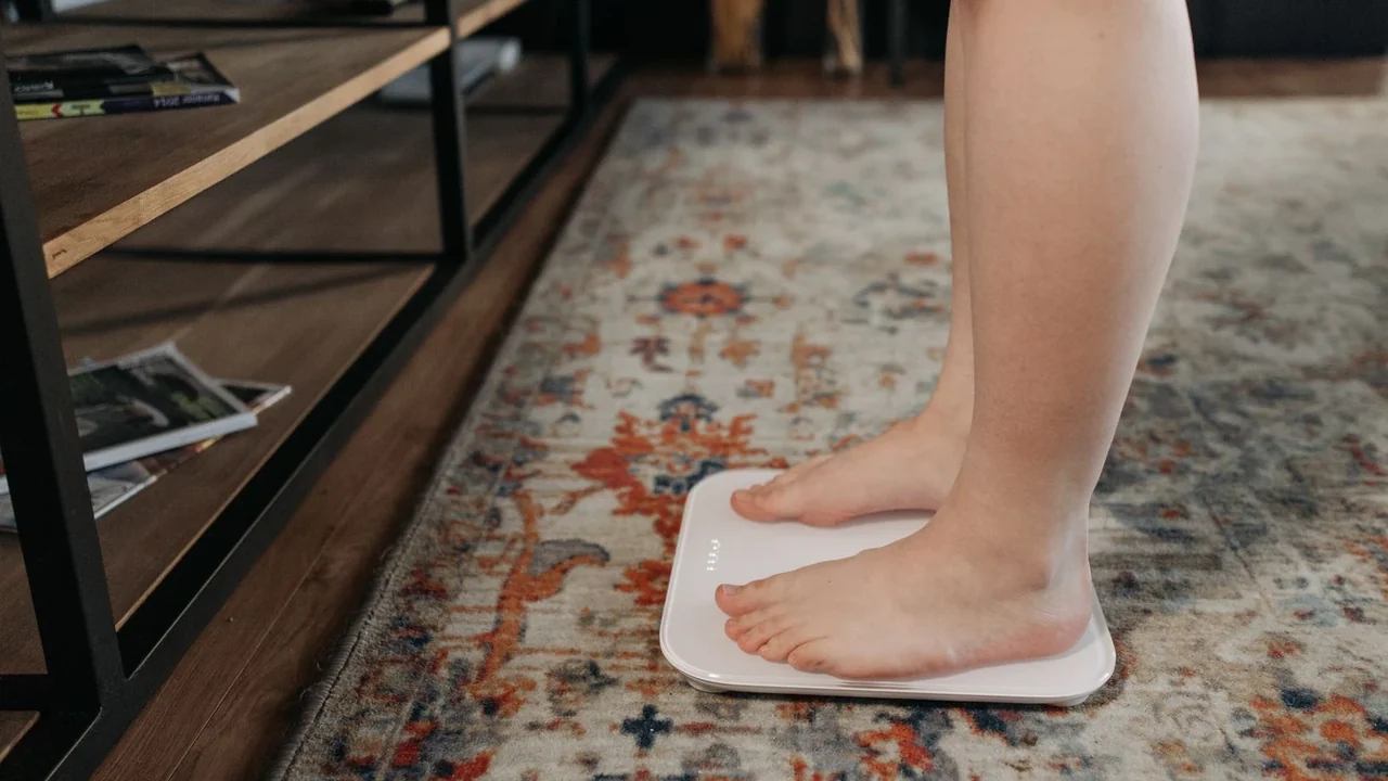 Bare feet on a bathroom scale over a patterned rug