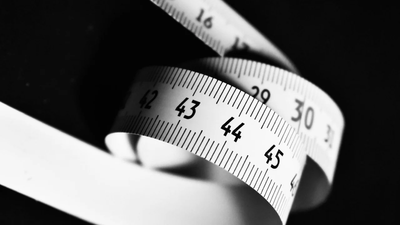 A curled measuring tape against a dark background